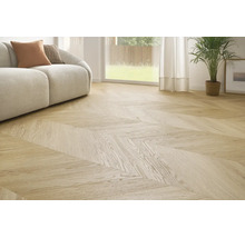 Sufragerie luminoasă cu pardoseală cu aspect de lemn cu model chevron, canapea modernă și plantă de interior în fața unei ferestre.