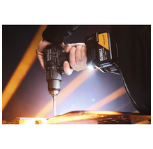 Persoană care utilizează o mașină de găurit 18 Volt cu DeWALT Logo, McLaren Logo și iluminare pentru a găuri o suprafață.