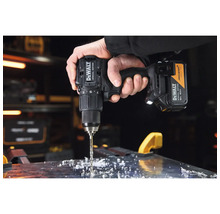 Mașină de găurit și înșurubat cu acumulator DeWALT Special Edition la găurirea unei plăci de metal cu așchii metalice.