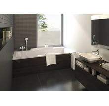 Baie modernă cu cadă dreptunghiulară albă, mască cu aspect de lemn închis la culoare, lavoar pe blat pe mobilier închis și fereastră mare.