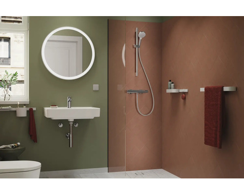 Baie modernă cu oglindă LED rotundă, chiuvetă albă, duș de tip walk-in cu plăci ceramice teracota și pereți verzi.