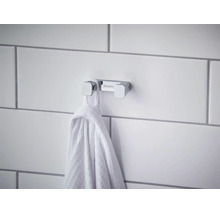 Agățătoare dublă pentru prosoape Hansgrohe din crom pe un perete placat cu faianță cu un prosop agățat.