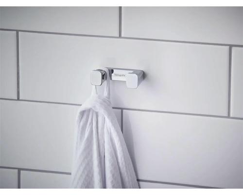 Agățătoare dublă pentru prosoape Hansgrohe din crom pe un perete placat cu faianță cu un prosop agățat.