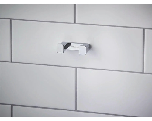 Cârlig dublu Hansgrohe din metal cromat pentru baie, montat pe un perete placat cu faianță.