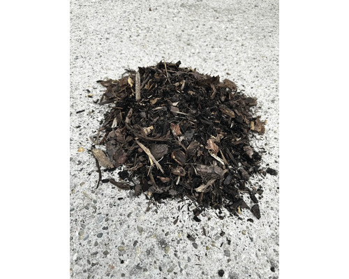 Mulci din scoarță de culoare închisă din bucăți de lemn pentru acoperirea solului în grădină.