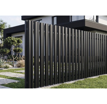 Gard modern de grădină din profiluri metalice verticale într-o grădină în fața unei case moderne.