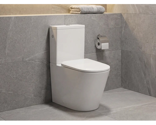 Vas WC de pardoseală modern din ceramică cu rezervor într-o baie cu plăci gri cu aspect de piatră naturală.