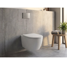 Vas WC suspendat într-o baie modernă cu aspect de beton, clapetă de acționare pe perete și un taburet din lemn cu prosoape și o plantă.