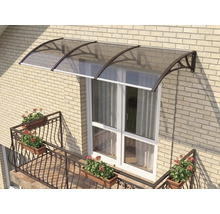 Copertină curbată pentru ușă cu acoperiș fumuriu și suporturi închise la culoare pe un perete din cărămidă deschisă deasupra unei uși de balcon albe.