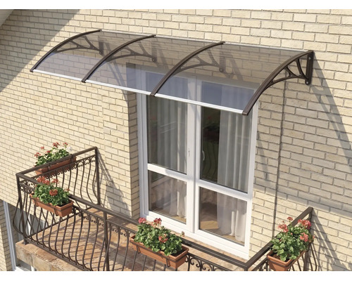 Copertină curbată pentru ușă cu acoperiș fumuriu și suporturi închise la culoare pe un perete din cărămidă deschisă deasupra unei uși de balcon albe.