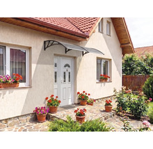 Copertină de ușă curbată deasupra unei uși de intrare pe o fațadă luminoasă cu jardiniere și pardoseală din piatră.