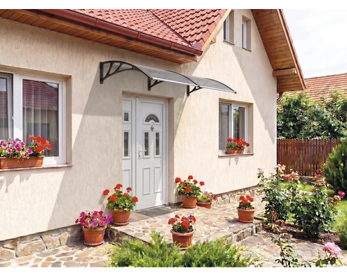 Copertină de ușă curbată deasupra unei uși de intrare pe o fațadă luminoasă cu jardiniere și pardoseală din piatră.