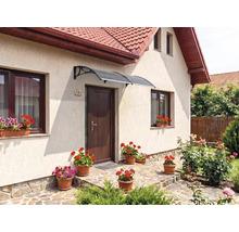 Copertină curbată deasupra unei uși de intrare într-o zonă de intrare decorată cu flori și pardoseală din piatră naturală.