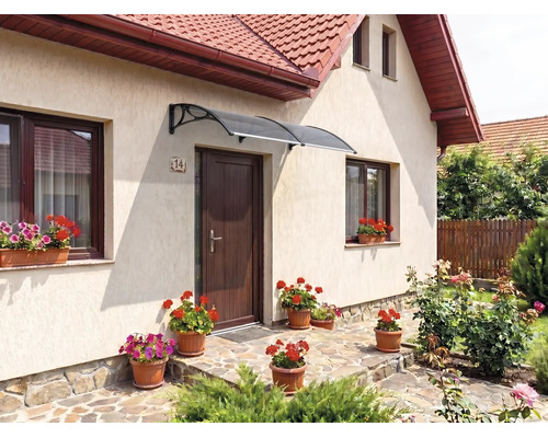 Copertină curbată deasupra unei uși de intrare într-o zonă de intrare decorată cu flori și pardoseală din piatră naturală.