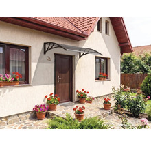 Copertină curbată pentru ușă cu suporturi închise la culoare deasupra unei uși de intrare pe o fațadă luminoasă cu jardiniere.