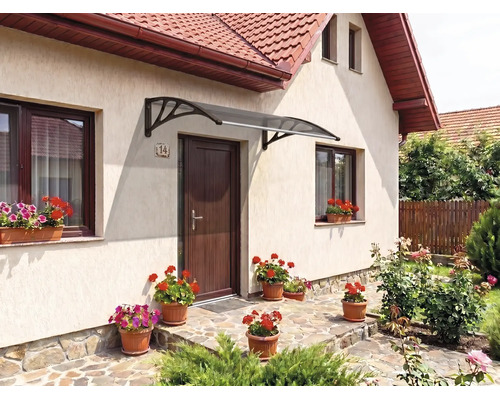 Copertină curbată pentru ușă cu suporturi închise la culoare deasupra unei uși de intrare pe o fațadă luminoasă cu jardiniere.