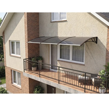 Copertină modernă din policarbonat deasupra unei ferestre pe un balcon luminos cu balustradă metalică și plante pe o fațadă de casă.