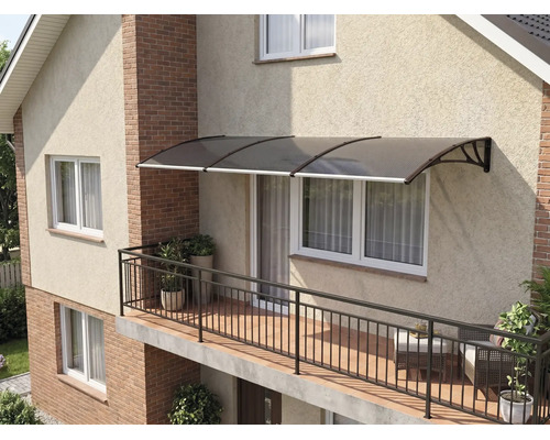 Copertină modernă din policarbonat deasupra unei ferestre pe un balcon luminos cu balustradă metalică și plante pe o fațadă de casă.
