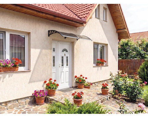 Copertină arcuită deasupra unei uși de intrare la o casă cu jardiniere și pavaj din piatră naturală.