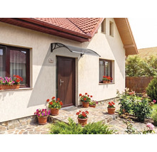 Copertină curbată modernă deasupra unei uși de intrare pe fațada unei case, cu jardiniere și o potecă de piatră.