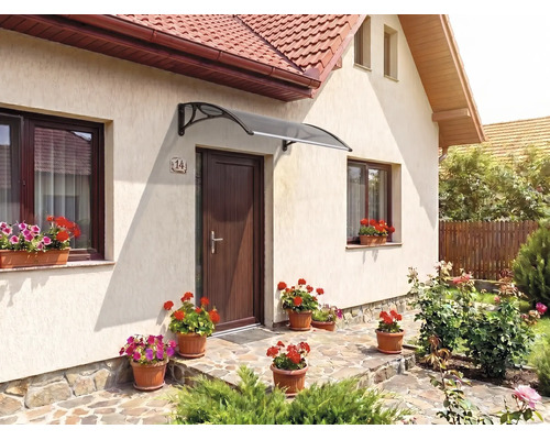 Copertină curbată modernă deasupra unei uși de intrare pe fațada unei case, cu jardiniere și o potecă de piatră.