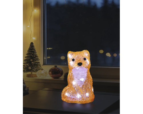 Figurină decorativă LED vulpe din acril cu lumină albă caldă într-o atmosferă de Crăciun pe o masă în fața unei ferestre.