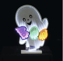 Decorațiune luminoasă pentru Halloween fantomă zâmbitoare cu efect de oglindă infinită și text Boo luminos pe un suport alb.