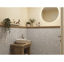 Baie modernă cu oglindă rotundă iluminată, lavoar alb pe mobilier din lemn rustic și faianță pătrată gri.