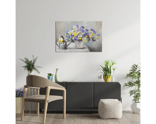 Tablou pe pânză cu motiv floral într-o vază și o stropitoare, suspendat deasupra unei comode într-o cameră luminoasă, mobilată modern.