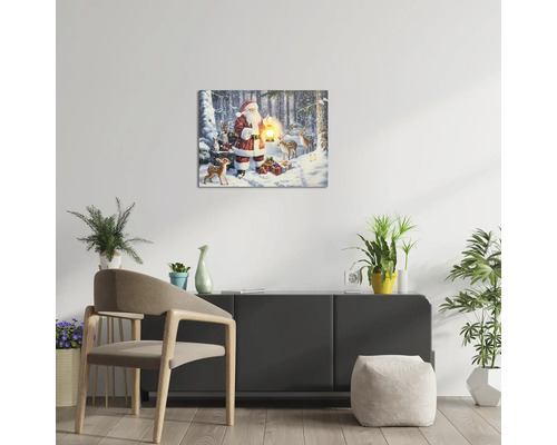 Living modern luminos cu tablou pe pânză cu LED cu Moș Crăciun și animale în zăpadă, suspendat deasupra unei comode cu plante de interior.