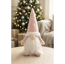 Pitic din material textil cu căciulă ascuțită și barbă pe o masă de lemn într-o cameră luminoasă, decorată festiv cu un brad de Crăciun.