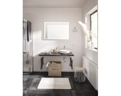 Baie modernă cu lavoar pe blat, oglindă iluminată, blat de lavoar, coș de rufe, radiator și accesorii de baie.