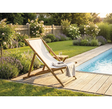 Șezlong din lemn cu pânză albă pe o terasă din lemn lângă o piscină într-o grădină cu lavandă și trandafiri.