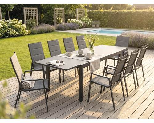 Set modern de dining pe o terasă din lemn cu masă mare din metal și scaune cu spătar înalt din textilenă într-o grădină luminoasă.