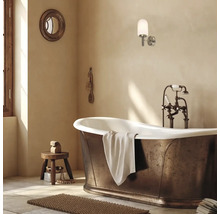 Cadă de sine stătătoare cu aspect de bronz, baterie nostalgică și aplică de perete modernă într-o baie luminoasă.