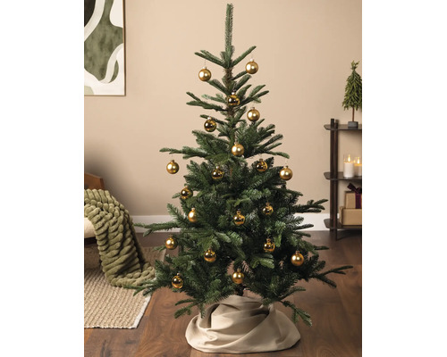 Brad de Crăciun artificial decorat cu globuri aurii și o fustă de brad bej într-o sufragerie.