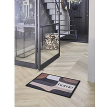 Hol modern cu un preș cu model geometric și inscripția home pe o podea în stil brăduț, lângă o ușă de sticlă.