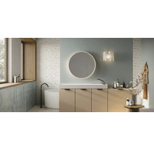 Baie modernă cu mască de lavoar bej, lavoar alb, oglindă rotundă și cadă de sine stătătoare în fața plăcilor ceramice cu model floral.