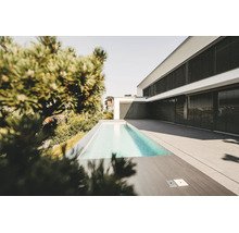 Casă modernă albă cu jaluzele exterioare negre, piscină dreptunghiulară îngustă și terasă spațioasă cu plăci de piatră gri.