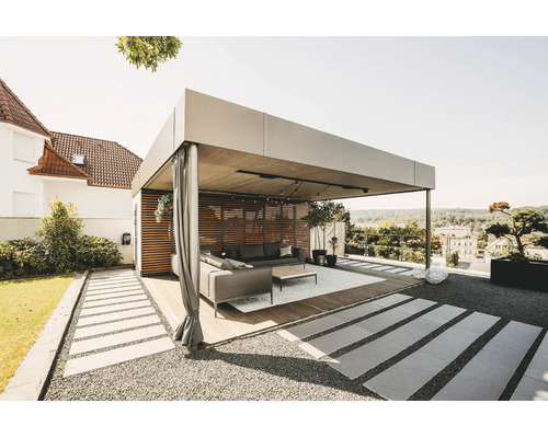 Pergolă modernă și luminoasă din metal, cu perete din lamele de lemn, perdele și mobilier de grădină pe o terasă din lemn.