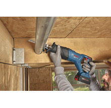 Utilizarea unui fierăstrău sabie cu acumulator Bosch pentru tăierea unei țevi metalice într-o construcție de tavan din lemn.
