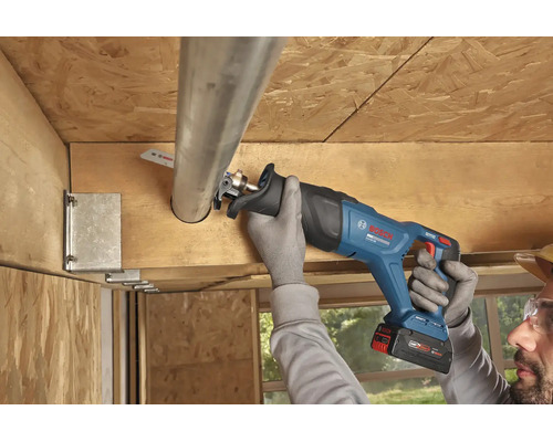 Utilizarea unui fierăstrău sabie cu acumulator Bosch pentru tăierea unei țevi metalice într-o construcție de tavan din lemn.