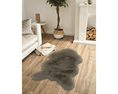 Covor din blană artificială gri închis într-o sufragerie luminoasă cu podea din lemn, canapea albă și șemineu.