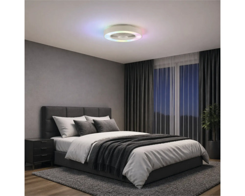 Ventilator de tavan modern cu inel LED colorat într-un dormitor cu pat tapițat gri, perdele închise la culoare și covor.