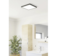 Baie luminoasă cu plafonieră LED pătrată, chiuvetă modernă, dulap înalt cu aspect de lemn și plantă de interior.