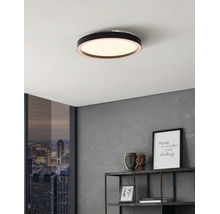Plafonieră LED rotundă și plată, neagră, montată pe un tavan alb într-un decor modern cu perete gri și raft metalic.