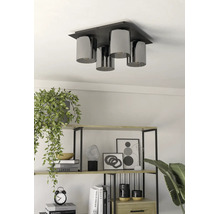 Plafonieră modernă cu 4 surse de lumină și abajururi cilindrice deasupra unui raft cu decorațiuni și plante.