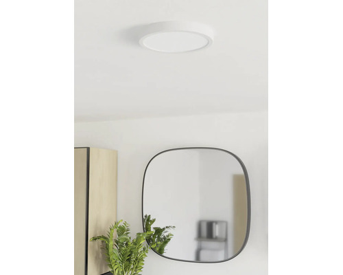 Plafonieră LED rotundă și plată montată într-o cameră luminoasă cu oglindă și plantă.