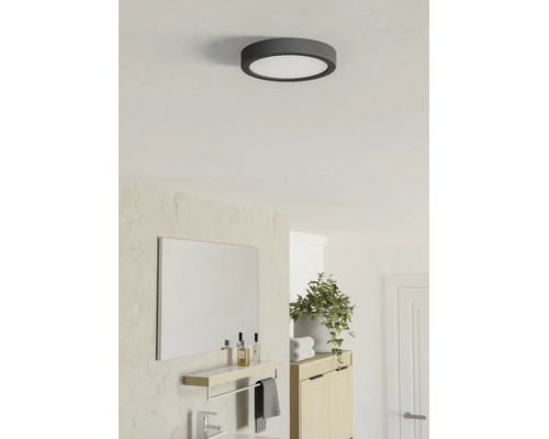 Plafonieră LED rotundă într-o baie modernă și luminoasă, cu oglindă, dulap din lemn și plantă.