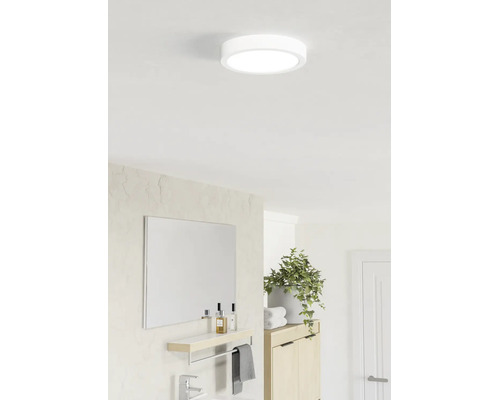 Plafonieră LED rotundă într-o baie luminoasă și modernă, deasupra unei oglinzi cu poliță și a unei plante de apartament.
